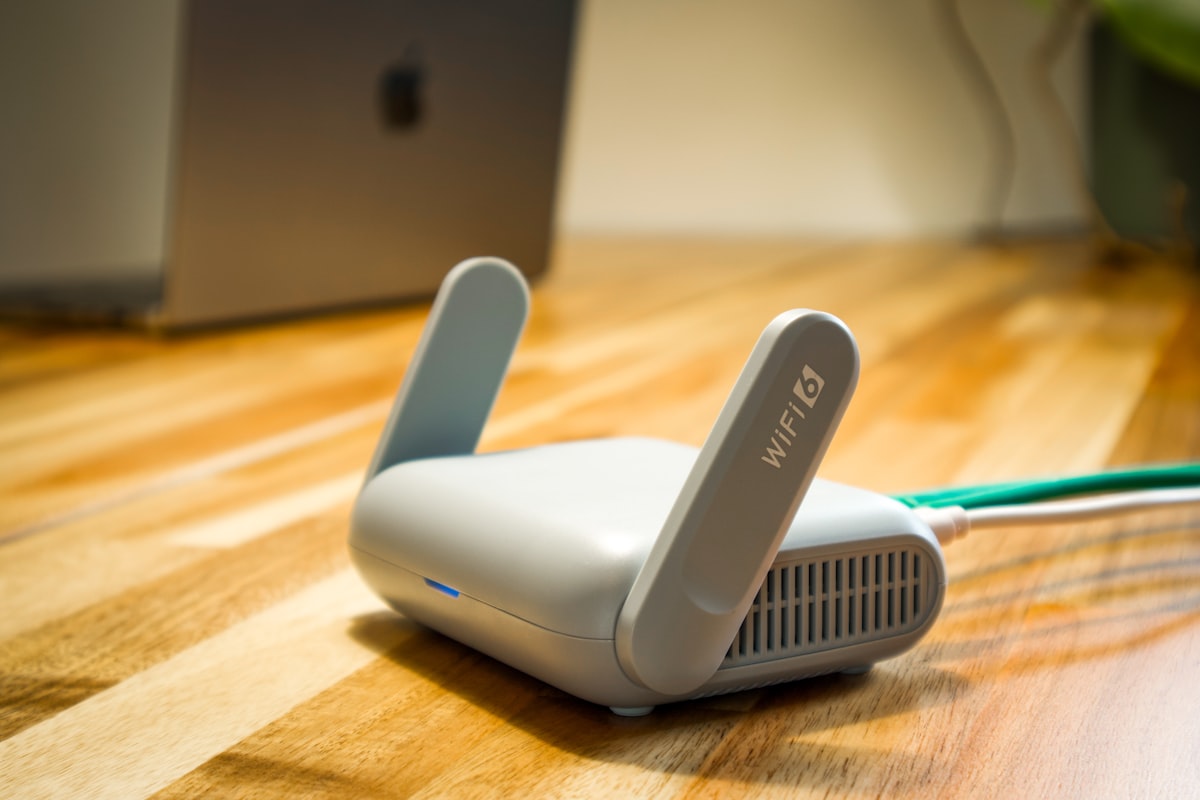 Home wi-fi router on a wooden floor beside a laptop